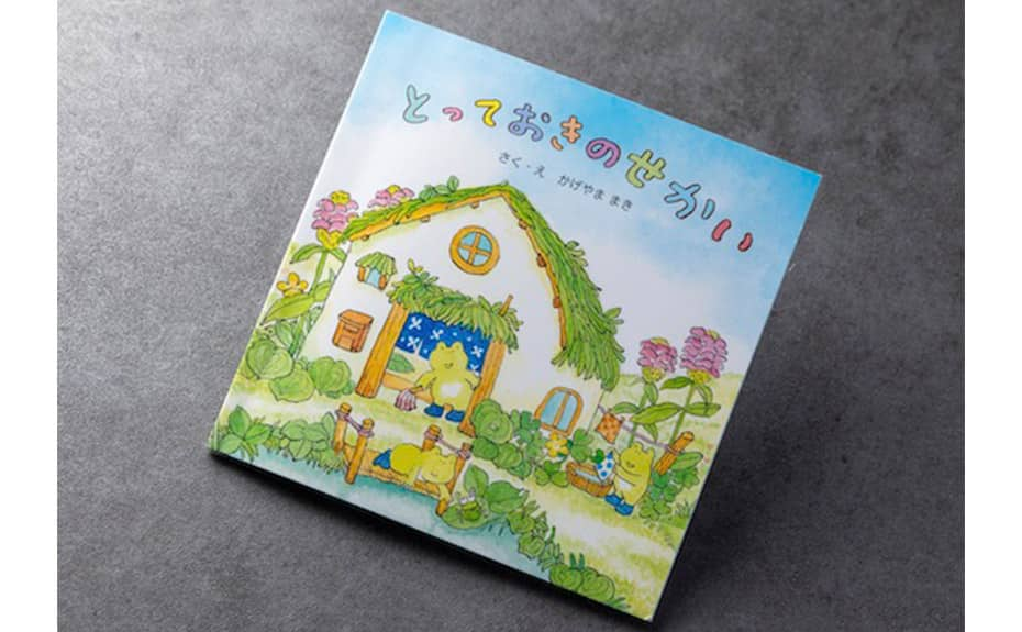 ANA Future Promise-themed picture book "Totteoki no Sekai" ("The Amazing World") cover image, watercolor of three frogs washing and cleaning in a hut by a pond.