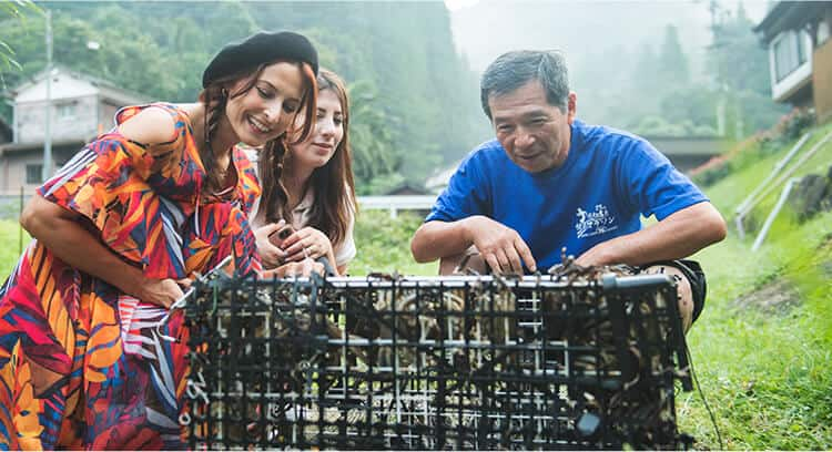 Kawachi−san’s husband and two women looking at the crab in the cage