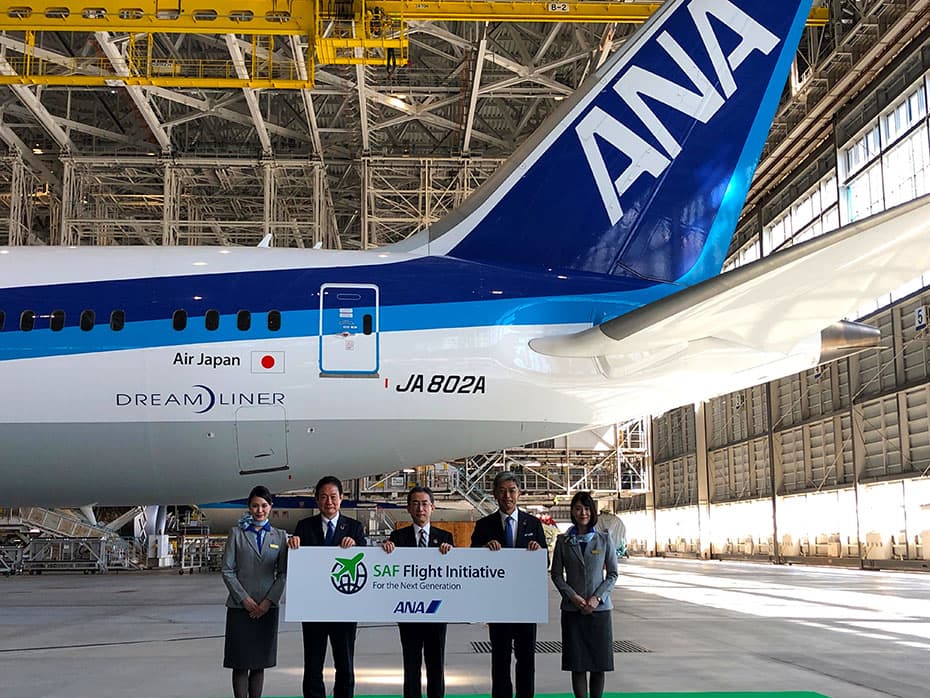 「SAF Flight Initiative： For the Next Generation」プログラム発表の様子。飛行機の前で役員と客室乗務員が「SAF Flight Initiative」の看板を持って立っています。